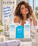 Three ELEVEN AUSTRALIA hair care products are displayed on a marble tray in a bright bathroom setting with a model in a white robe in the background. The products include a white bottle of Hydrate My Hair Moisture Shampoo, a blue 3-Minute Repair treatment bottle, and a white bottle of Hydrate My Hair Moisture Conditioner - Hair Care Canada
