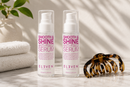 Two bottles of 'Smooth & Shine Anti-Frizz Serum' by Eleven on a surface with a hair comb and towel in the background  Hair Care Canada