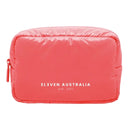 A bright coral pink puffer-style cosmetic pouch with white text reading 'ELEVEN AUSTRALIA est. 2011' on the front, shown on a plain white background.