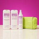 A haircare set from ELEVEN AUSTRALIA including Smooth Me Now Anti-Frizz Shampoo, Smooth Me Now Anti-Frizz Conditioner, Smooth Me Now Thermal Spray, and a lime green zippered pouch, arranged on a reflective white surface against a vibrant magenta-pink background.