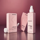 Three Kevin Murphy haircare products in a coordinated blush pink color: Angel Wash shampoo, Angel Shine conditioner, and Anti-Gravity hair spray, arranged on a reflective surface against a dusty rose background.