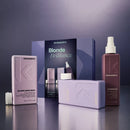 Kevyn Murphy Blonde Brilliance haircare set on a reflective dark surface, featuring a lavender Angel Shampoo box, a mauve Unstyled Styler bottle, and a dark blue product box in the background.