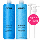 Two blue Amika Hydro Rush shampoo and conditioner bottles shown on a white background, with two white pump dispensers to the right and a pink circle that reads FREE PUMPS.