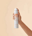 Hand holding a can of 'Dry Finish Texture Spray' against a beige background - Hair Care Canada