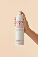 Hand holding a can of 'Give Me Hold Flexible Hairspray' by Eleven on a beige background - Hair Care Canada