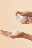 Person holding a bottle of 'Want Body' volume foam with a beige background - Hair Care Canada