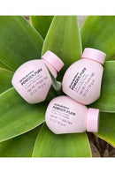 Three pink jars of Kevin Murphy Powder Puff face powder arranged on large green leaves.